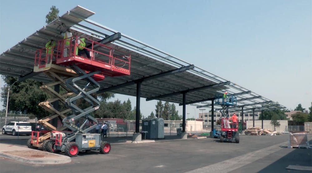 Workers install a solar panel canopy in the Fresno school district.