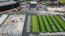 Workers install turf for the new football field at Ching Stadium