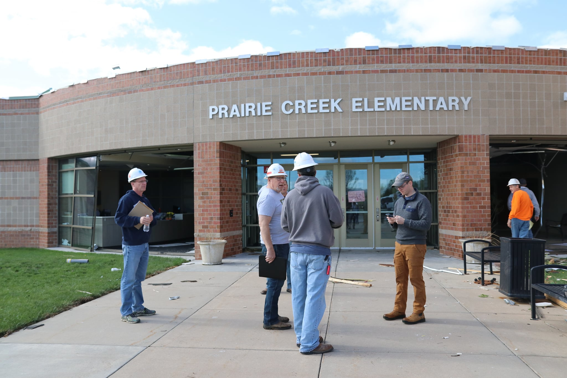 Officials stand outside Prairie Creek Elementary School in Andover, Kan., and discuss the damage from the EF3 tornado