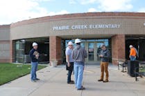 Officials stand outside Prairie Creek Elementary School in Andover, Kan., and discuss the damage from the EF3 tornado