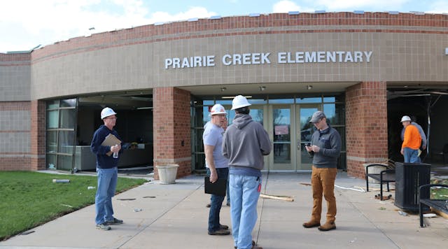 Officials stand outside Prairie Creek Elementary School in Andover, Kan., and discuss the damage from the EF3 tornado