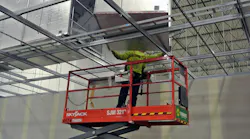 Man on lift installing duct work in industrial facility.