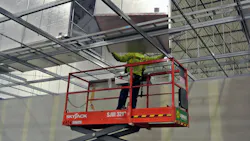 Man on lift installing duct work in industrial facility.