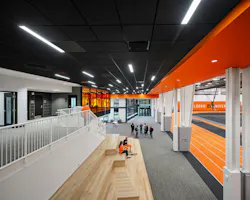 Large athletic space with wooden stadium-type seating at bottom of staircase