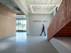 Interior lobby of Kemper Hall with a staircase, exposed ceiling systems, and signage for the building.
