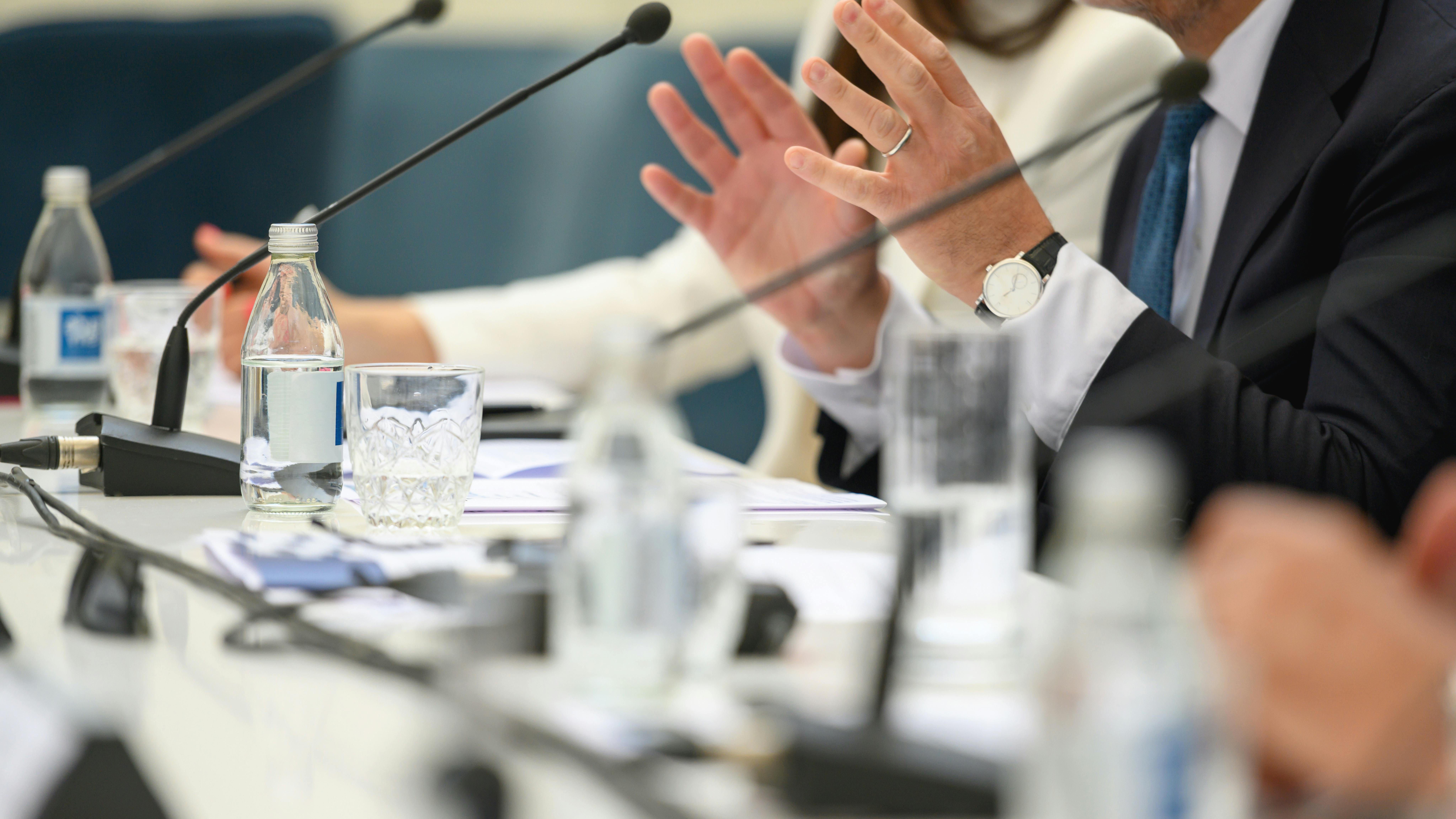 Close up of man's hands gesturing behind microphone at board meeting.