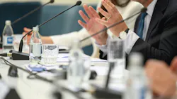 Close up of man's hands gesturing behind microphone at board meeting.