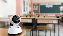 A security camera on a school desk with classroom blurred in the background.