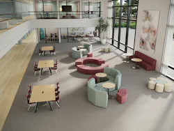 An open-plan commons in educational setting with task chairs and work tables, as well as more informal seating areas for gathering