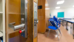 Close-up of door handle and lock with classroom blurred in background.