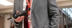 Close-up of midsection of man dressed in suit holding handheld radio.