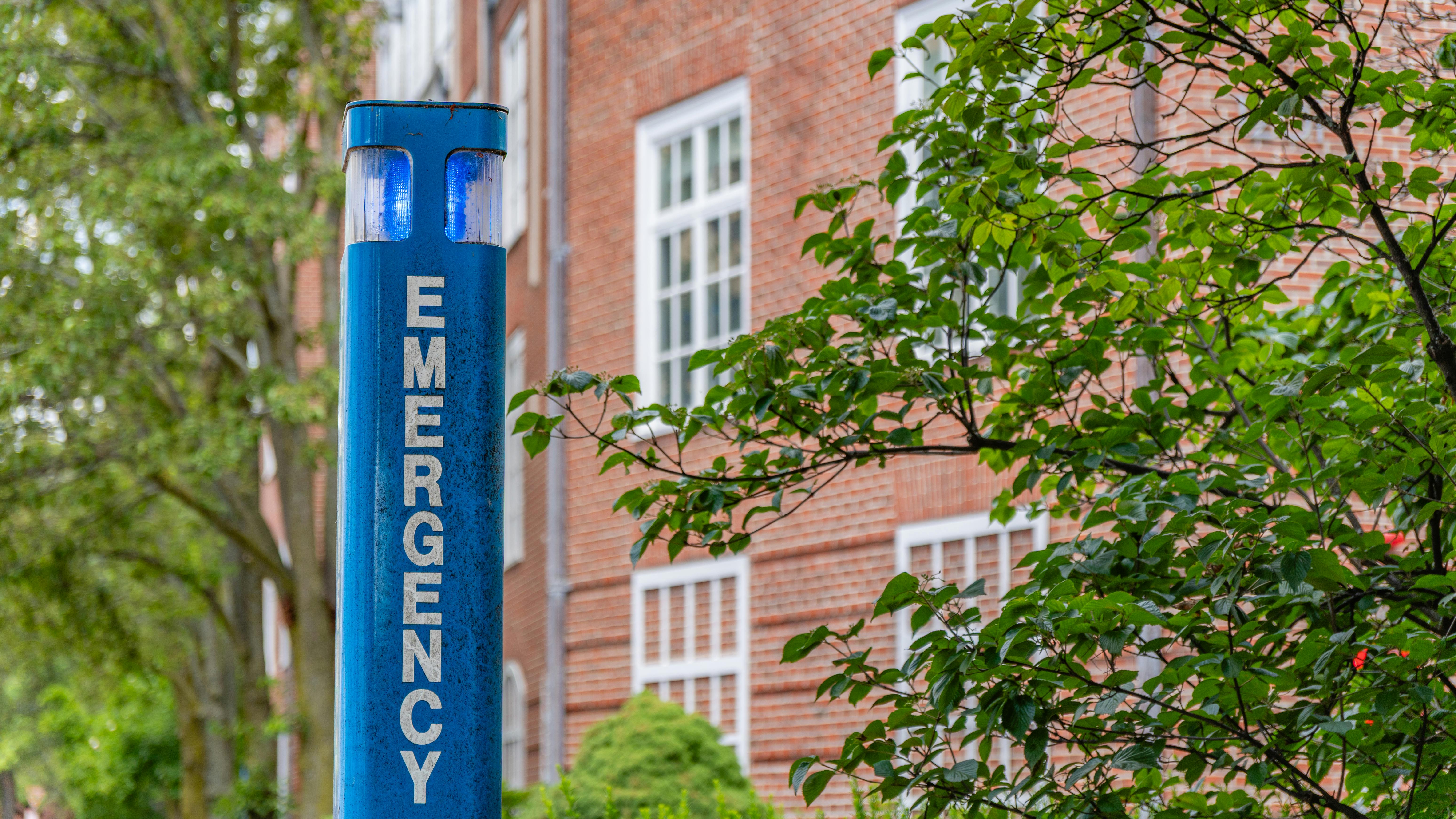 Close-up of blue emergency station at university campus.