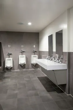 Modern men's restroom with integrated sink in foreground and urinals in background.