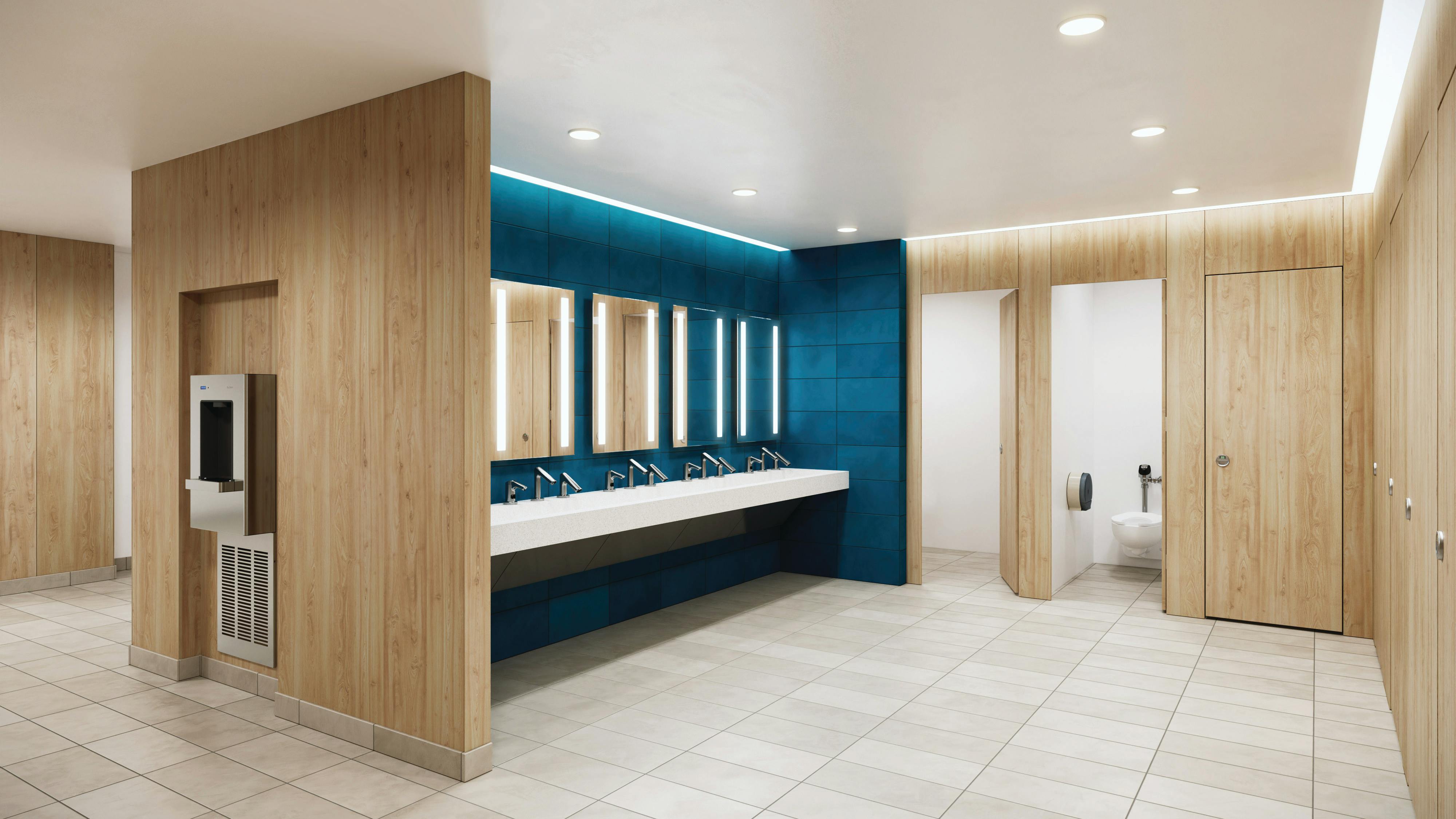 Contemporary restroom with full-height stalls in wood finish with integrated sinks in foreground against teal wall.