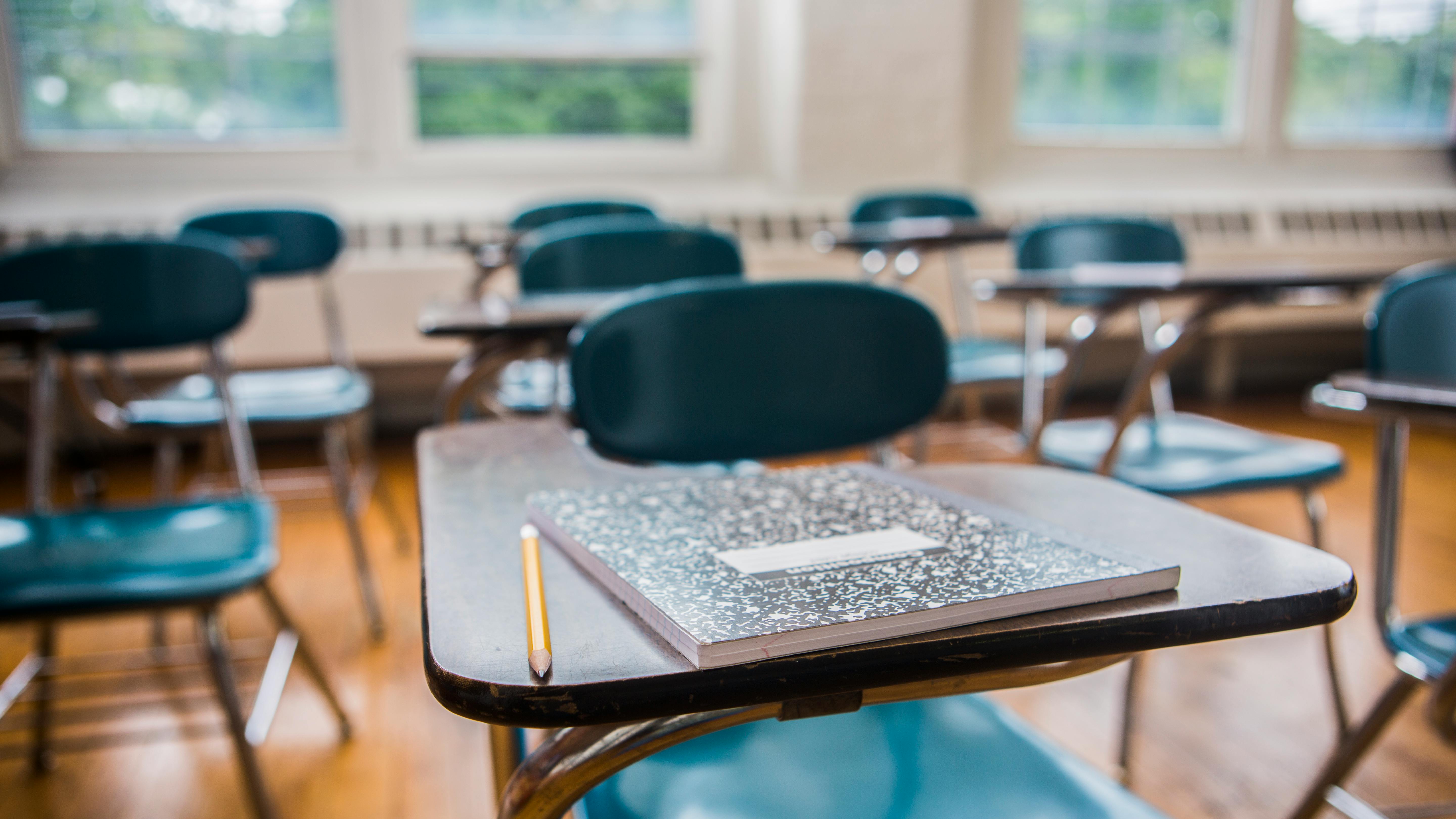 Close-up of student desk with notepad and pencil in empty classroom