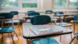 Close-up of student desk with notepad and pencil in empty classroom
