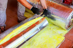 Close-up of worker wrapping HVAC duct with fiberglass insulation.