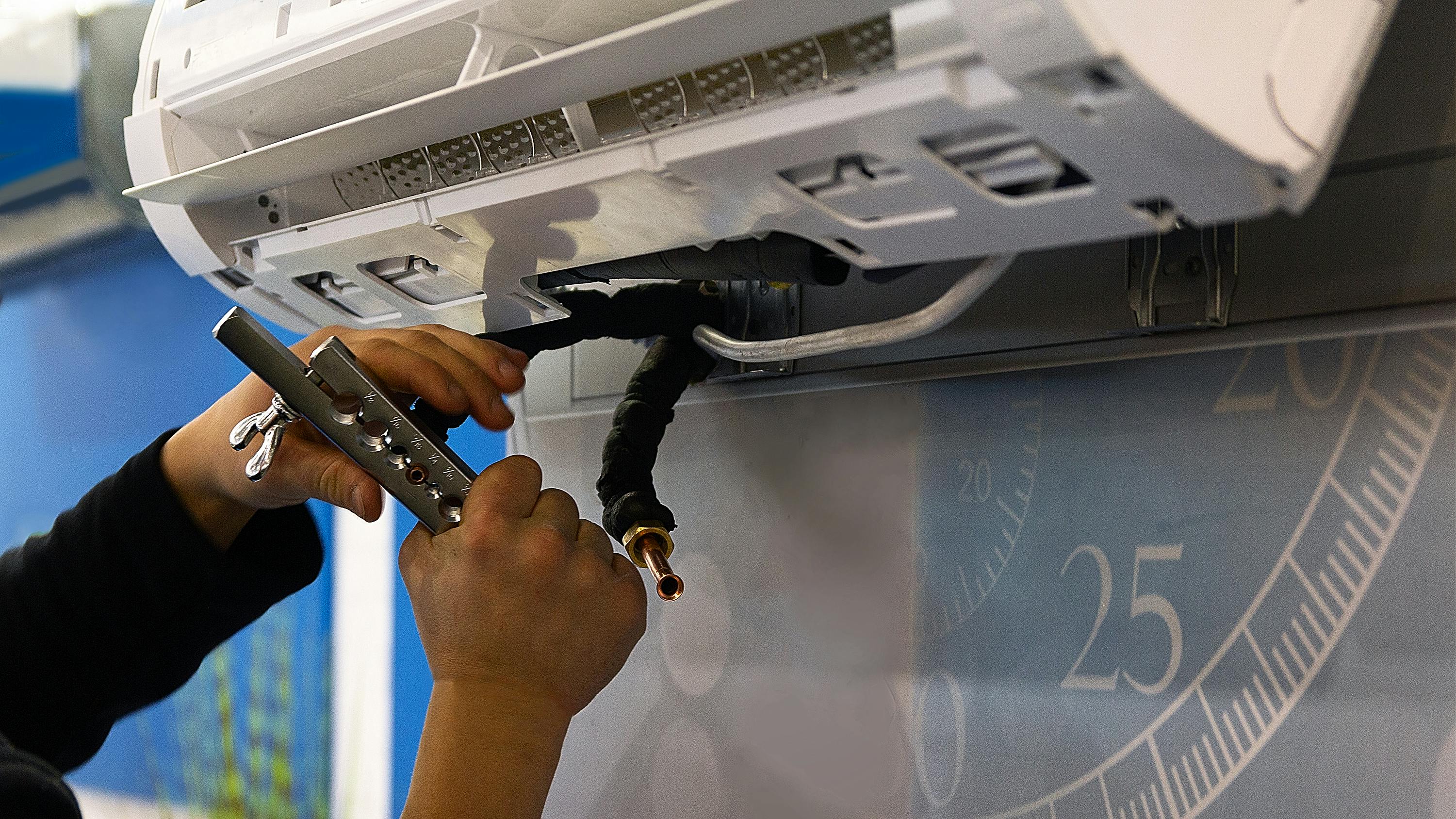 Close up of HVAC technician's hands installing a wall-mounted air conditioning unit.