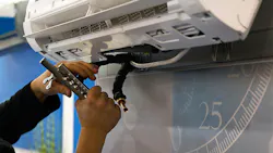Close up of HVAC technician's hands installing a wall-mounted air conditioning unit.