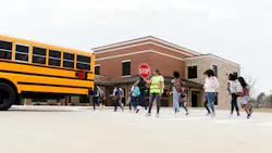 Children get off school bus with crossing guard on duty.