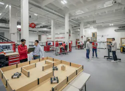 Robotics lab with people standing and talking near equipment.
