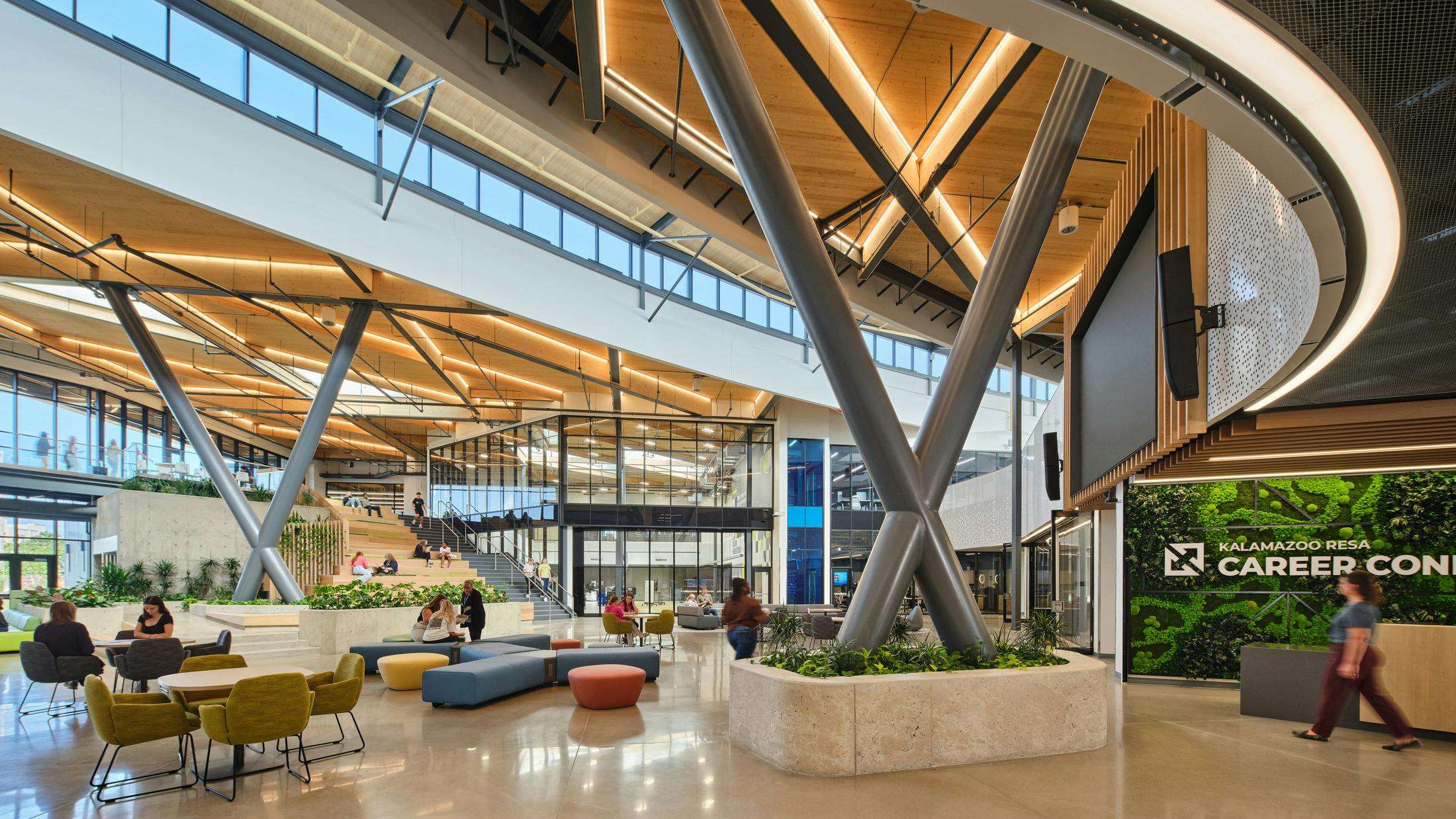 Expansive two-story atrium/lobby space at career learning center with clerestory windows, lounge seating with planters.