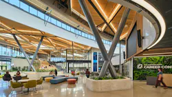 Expansive two-story atrium/lobby space at career learning center with clerestory windows, lounge seating with planters.