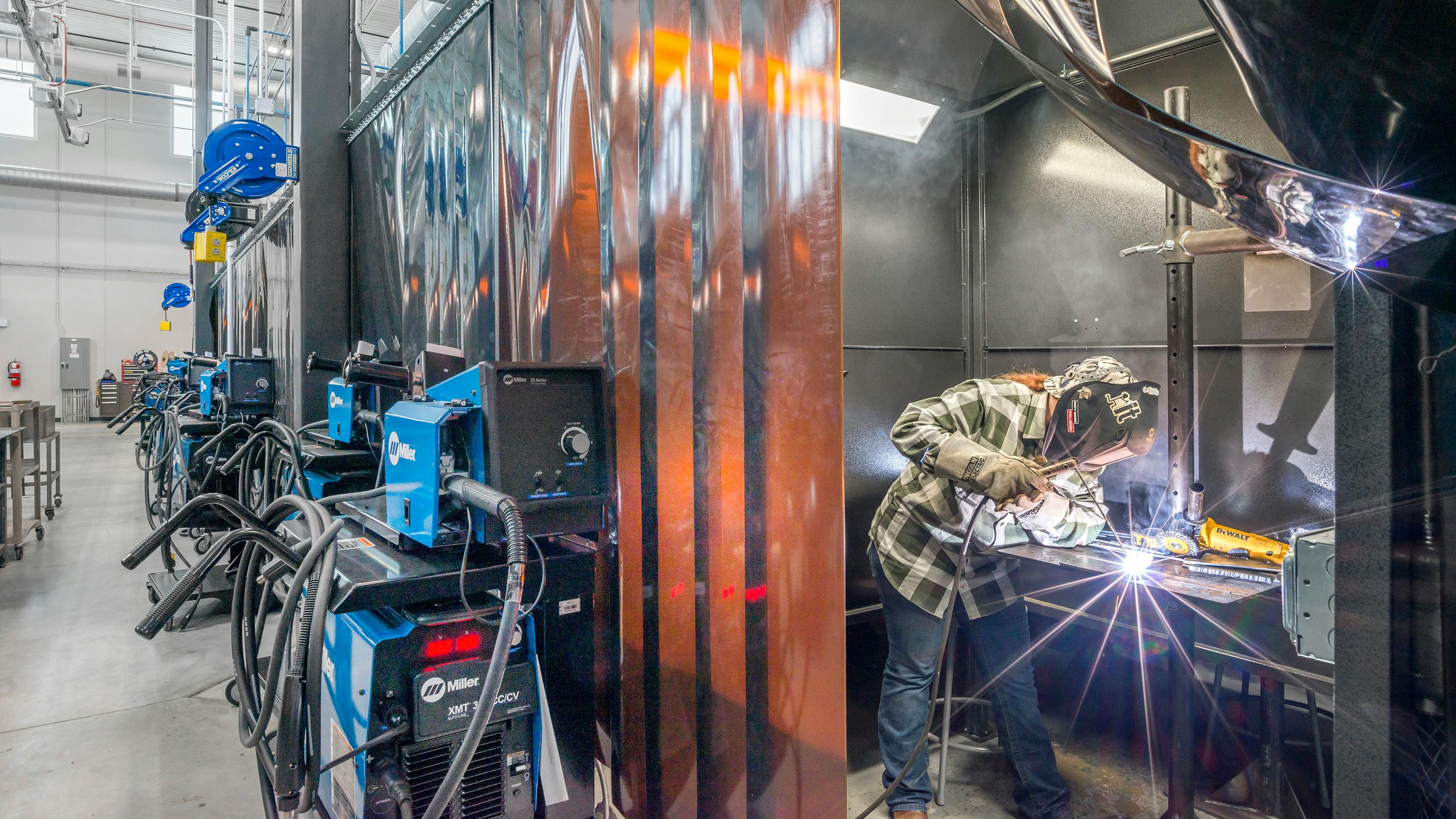 Student working on welding bench wearing personal protection equipment.