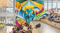 Students sit on reading stair next to large, colorful wall mural of an owl by a local Colorado artist.