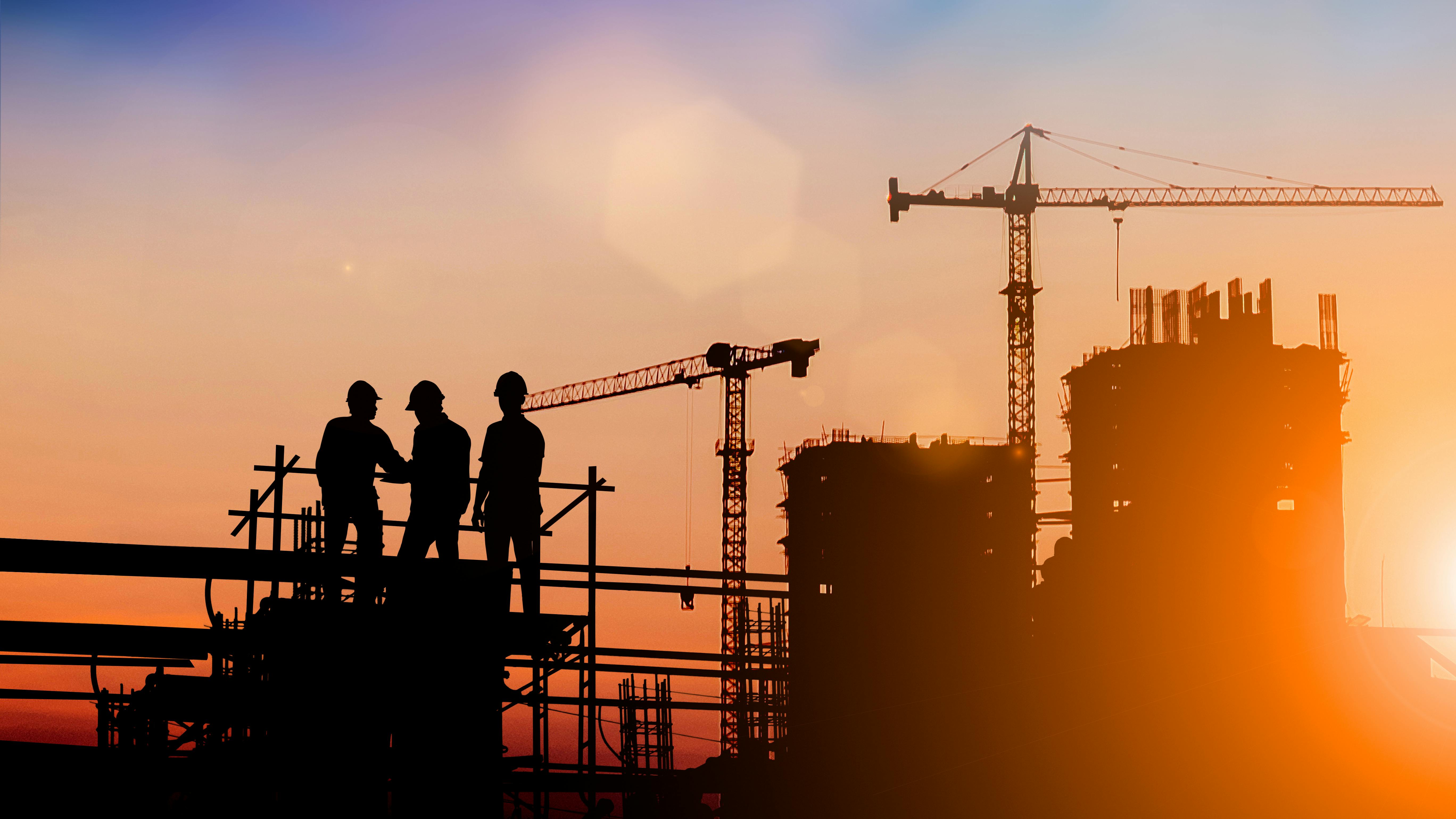 Silhouette of construction workers on construction site at dusk.