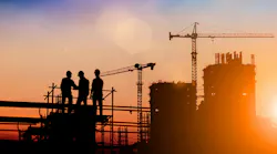 Silhouette of construction workers on construction site at dusk.