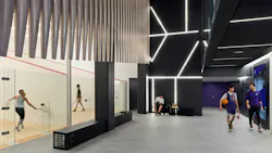 Modern college athletic center with indoor racquetball courts and students walking in hallway with basketball.