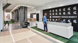 Reception area with student talking to receptionist against black wall with university logo.