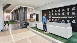 Reception area with student talking to receptionist against black wall with university logo.