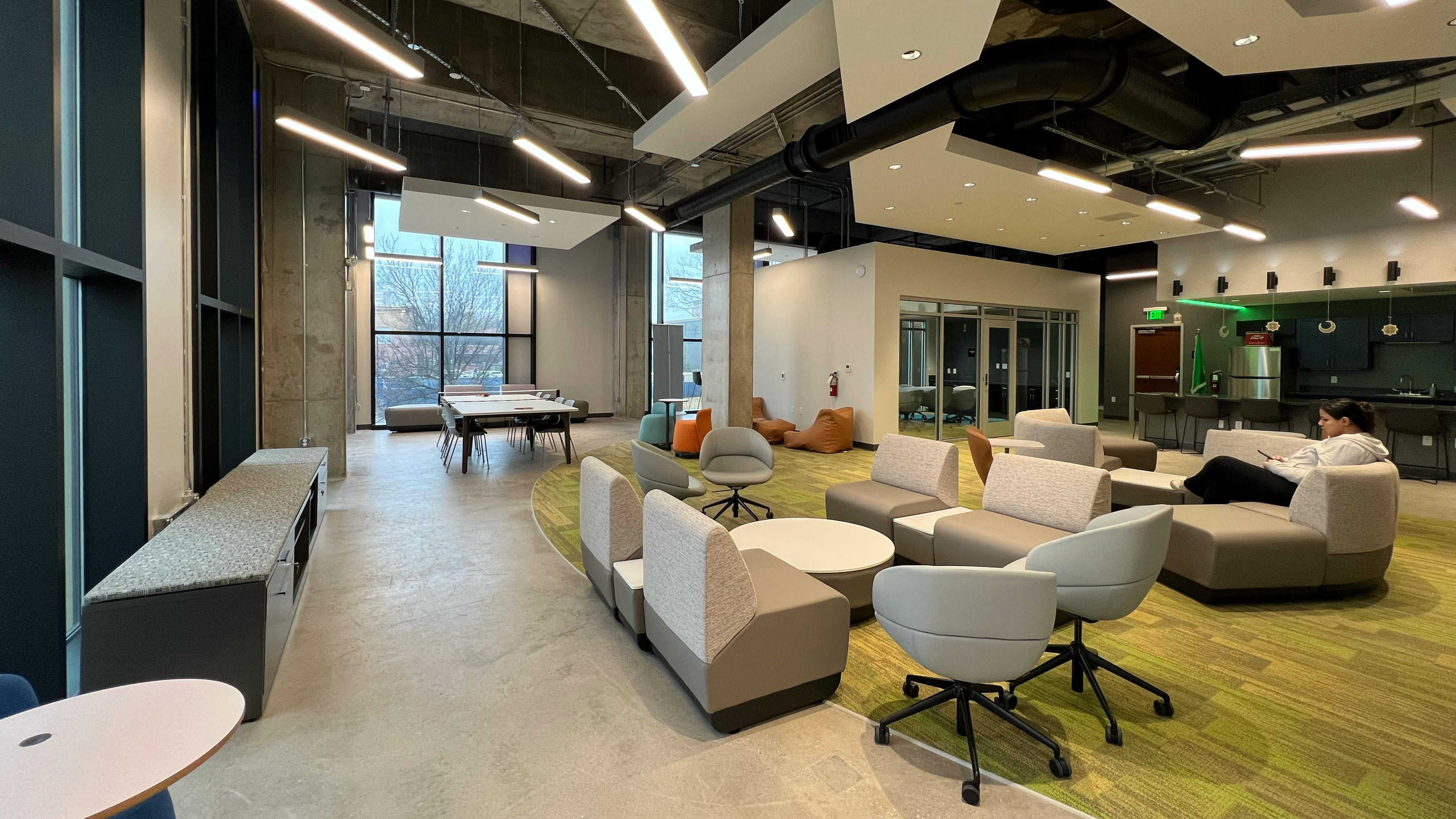 Lounge area with student studying in comfortable seating with modern light fixtures overhead.