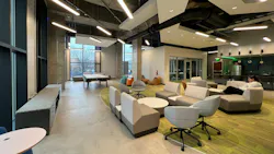 Lounge area with student studying in comfortable seating with modern light fixtures overhead.