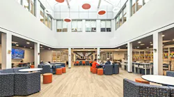 Bright, two-story daylight atrium with skylights and a variety of colorful lounge seating occupied by students.