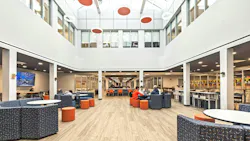 Bright, two-story daylight atrium with skylights and a variety of colorful lounge seating occupied by students.