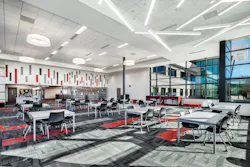 Expansive, modern media center with tables and chairs in foreground and book cases in background.