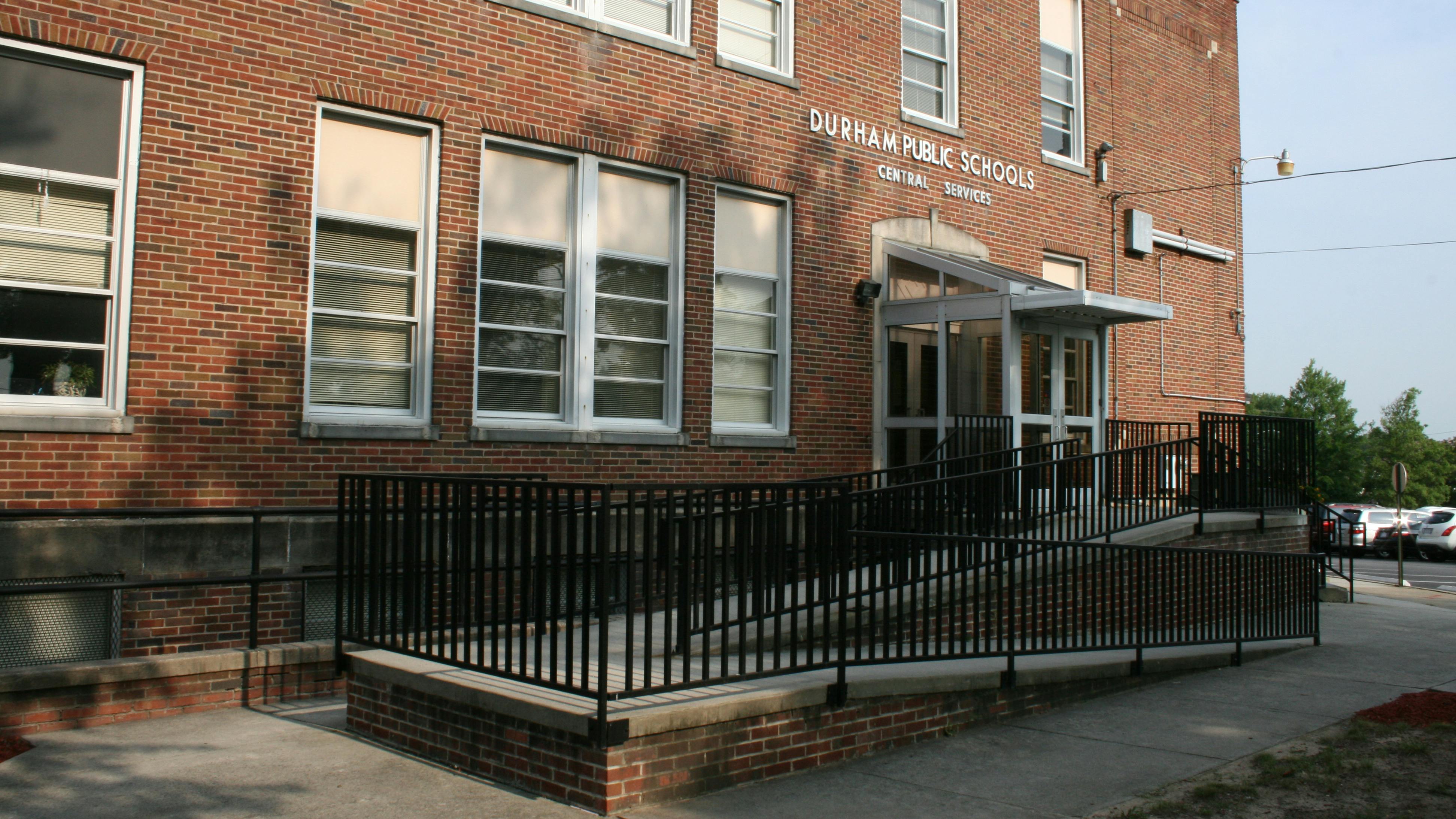 Exterior of brick building housing Durham County School office with accessibility ramp leading to entrance.