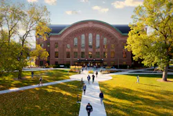 Exterior of historic, brick Montana State University building and lawn area with students walking on paths.