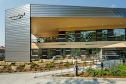 Exterior view of modern educational building at Montana State University with metal facade and glass, and landscaping lining walkway to entrance.