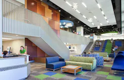 Modern student commons area with lounge seating in front of stadium stairs with students studying.