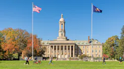 The Old Main building on the campus of Penn State University in autumn sunny day with students walking and biking.