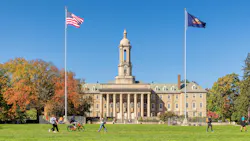 The Old Main building on the campus of Penn State University in autumn sunny day with students walking and biking.