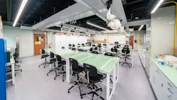 Modern science classroom with glass-top tables and stool-height chairs.
