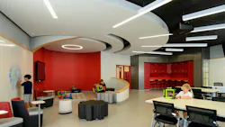 Modern classroom with variety of seating areas, writable walls, and oculus-shaped ceiling with lighting fixtures extending outward.