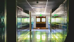Distant double entry doors in empty school hallway lined with lockers