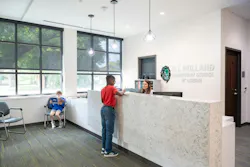 Student stands at reception desk in main office talking to receptionist.