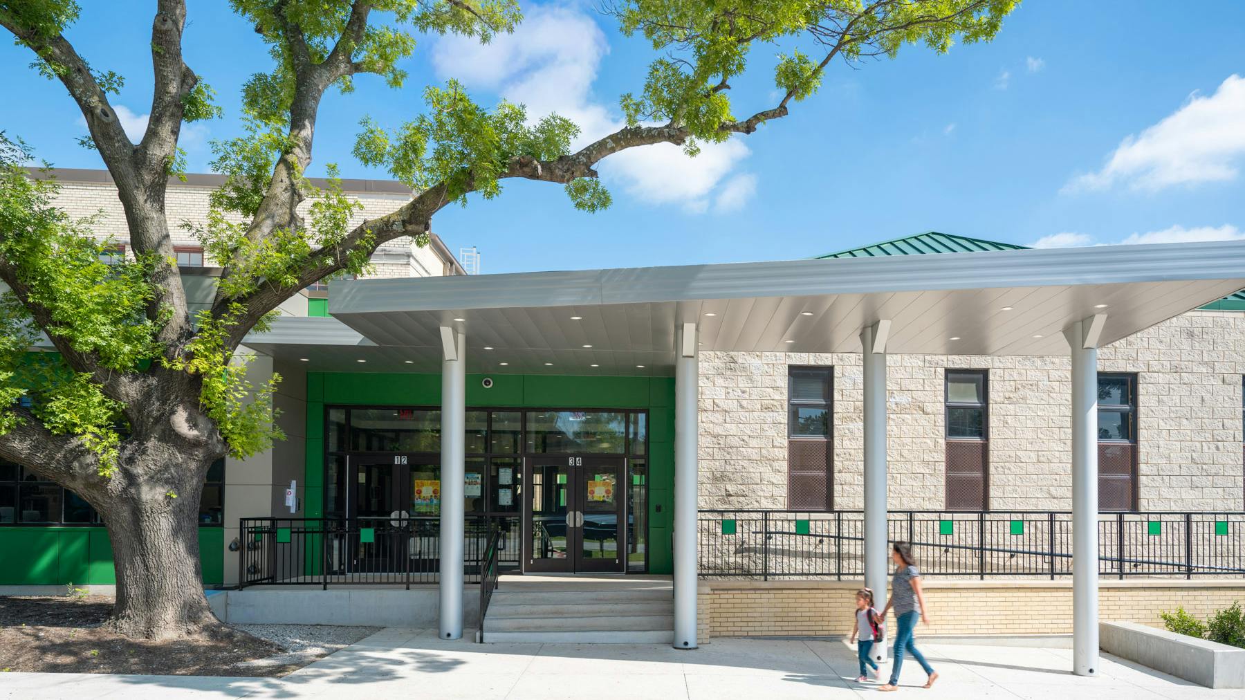Parent and child walk under covered entrance to newly remodeled elementary school.